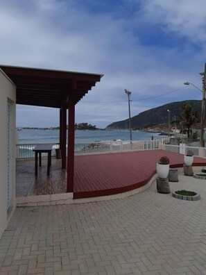 A covered outdoor area with a red floor, a table, and potted plants. - Frente Mar (Florianópolis)