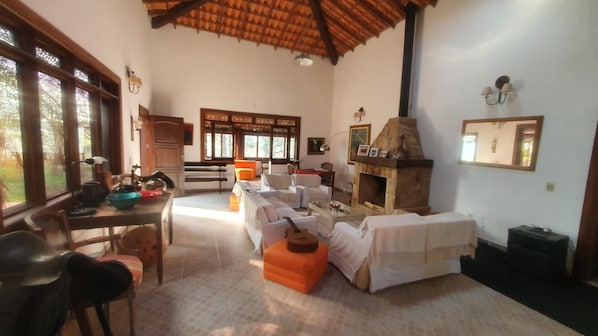 Uma sala de estar ampla com lareira, assentos e área de jantar.