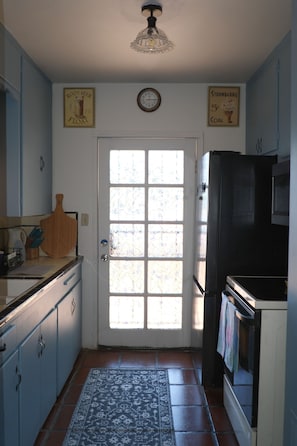 A kitchen with a refrigerator, a clock, and a window with frosted glass. - Historic charming 2-bedroom house with AC in welcoming Tucson (Tucson)