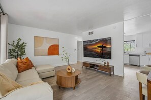 A modern living room with a sofa, a coffee table, and a TV. - LongBeach Cottage - Pool, Spa, Games, 4Miles2Beach (Long Beach)