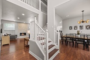 A modern interior with a staircase, a dining area, and a living room with a fireplace. - Hot Spa Private Oasis Also Available for long term (McKinney)