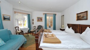 Quarto de hotel com cama, sofá, mesa de jantar com cadeiras e janela com cortinas.