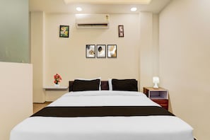 Une chambre d’hôtel avec un lit, une table de chevet, une lampe et des œuvres d’art murales.