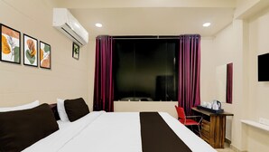 Ein Hotelzimmer mit einem Bett, einem Schreibtisch mit Stuhl, einem Flachbildfernseher und Bildern an der Wand.