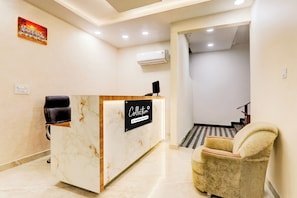 A reception desk with a sign, a black office chair, a marble floor, and a staircase leading to another area. - Collection Kakadeo Kanpur Formerly Avon (Kanpur)