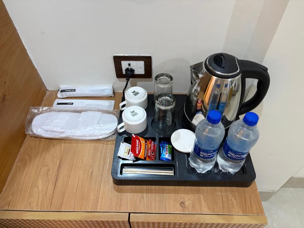A hotel room's minibar with a coffee maker, tea kettle, water bottles, and snacks.