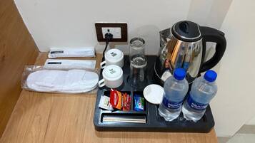 Minibar de una habitación de hotel con cafetera, tetera, botellas de agua y refrigerios.