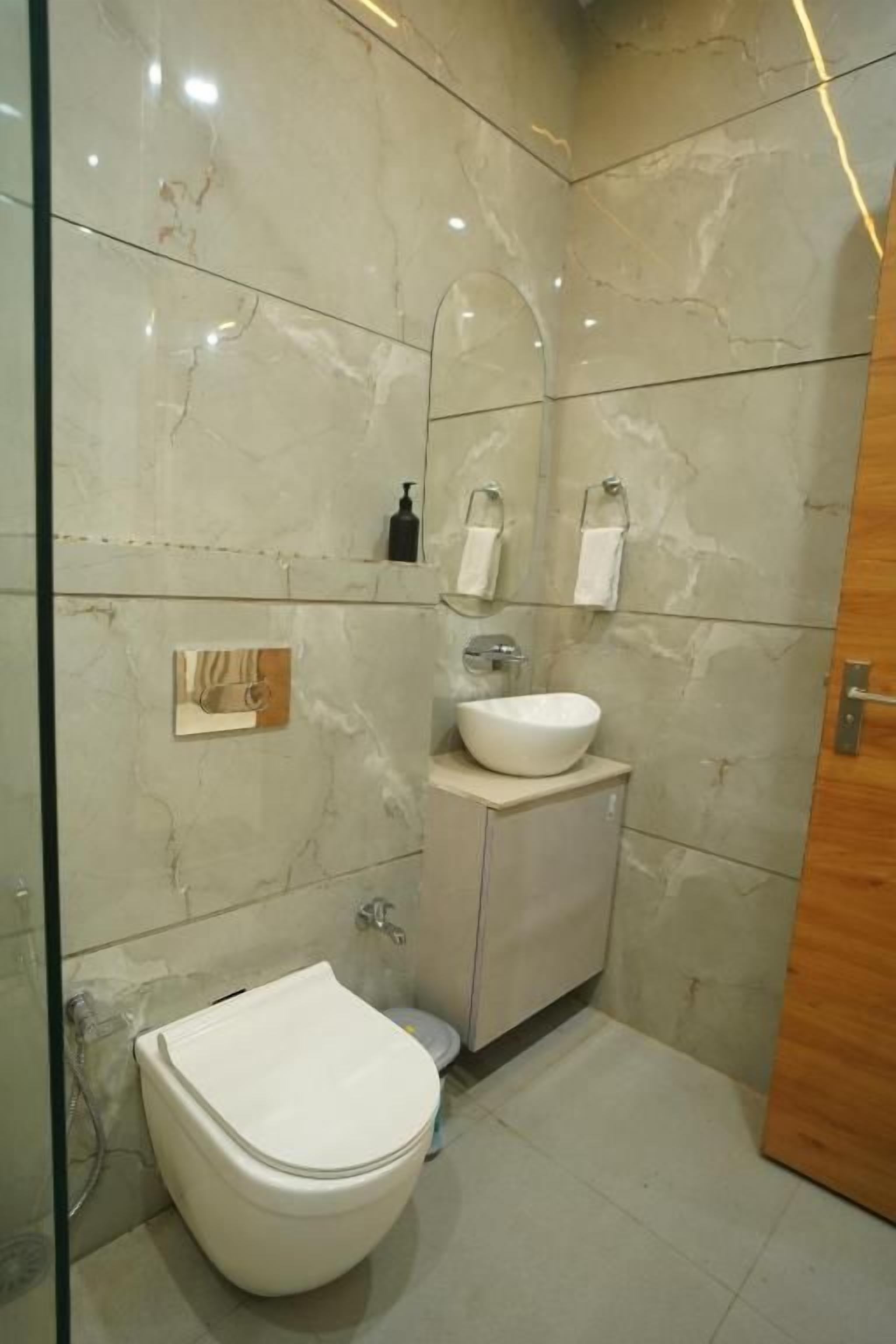A bathroom with a toilet, sink, and mirror.