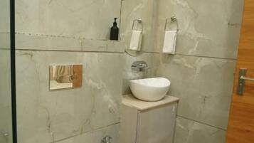 A bathroom with a toilet, sink, and mirror.