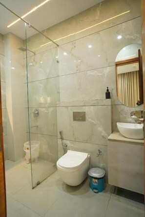 Un baño moderno con ducha envuelta en vidrio, inodoro y lavabo con espejo arriba.