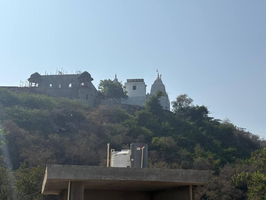 A building with a dome and a smaller structure on a hill, surrounded by trees.