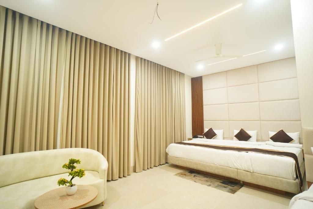 A modern hotel room with a large bed, a sofa, and a small table with a plant.