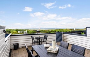 Eine Terrasse im Freien mit Tisch, Stühlen, einer weißen Kanne und einem Tablett mit Tassen.