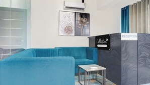 Ett väntrum med en blå soffa, ett litet bord och en skylt som visar att det är en utlämningsplats för företagets tjänster.