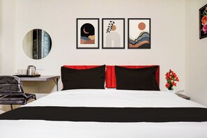 Una habitación de hotel con una cama, un escritorio y una silla. Hay tres obras de arte enmarcadas en la pared.