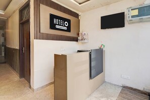 A hotel reception desk with a sign indicating it is company-serviced. - Super Hotel O GMS Road Formerly The Nest (DEHRADUN)