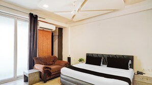 A modern hotel room with a large bed, a brown leather armchair, and a small table. - Super Hotel O GMS Road Formerly The Nest (DEHRADUN)