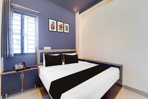A hotel room with a bed, a nightstand, a window with curtains, and wall art. - Super Hotel Nagamalaipudukottai Madurai (Madurai)
