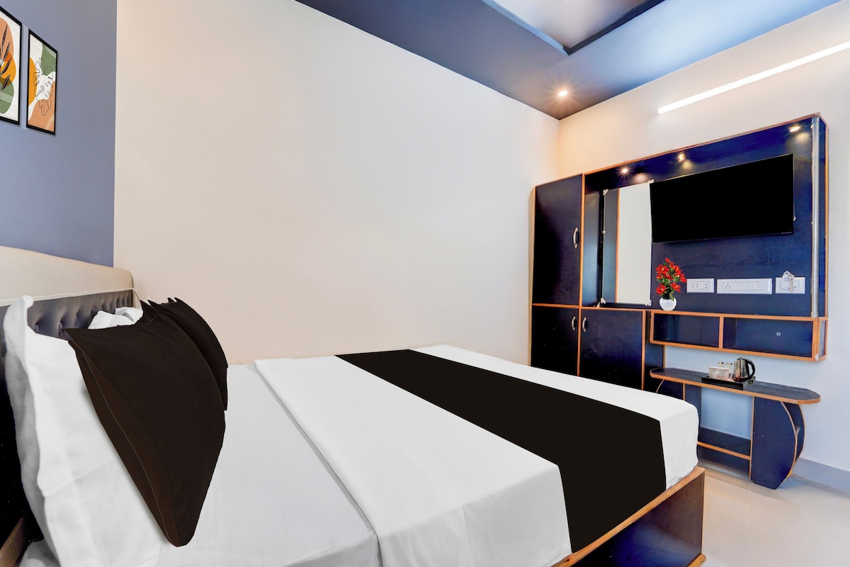 A modern bedroom with a bed, a wardrobe, a TV, and a small table with a vase.