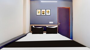 Una habitación de hotel estrecha con cama, escritorio y puerta.