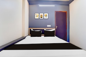 A narrow hotel room with a bed, a desk, and a door. - Super Hotel Nagamalaipudukottai Madurai (Madurai)