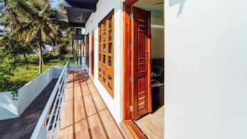 A corridor with wooden doors and windows, a white wall, and a wooden floor.
