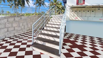 A staircase with a checkered floor leading to a building with a red window and a row of cabinets.
