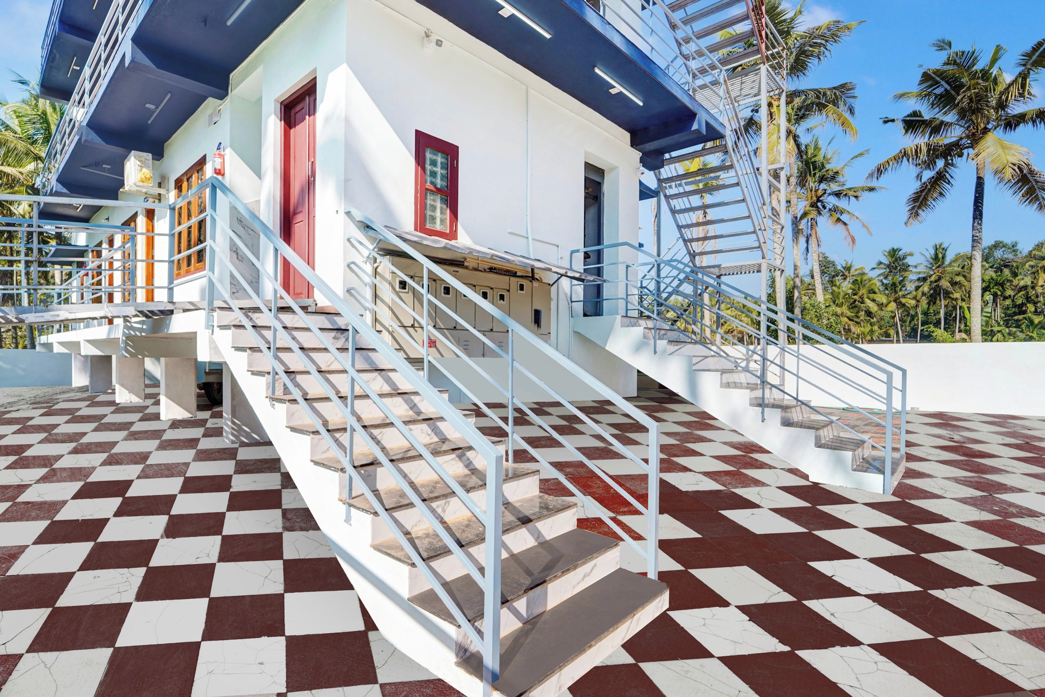 Un bâtiment avec un sol à carreaux, un escalier doté de rampes en métal et une porte rouge.