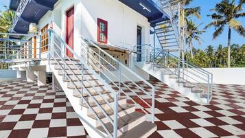 A building with a checkered floor, a staircase with metal railings, and a red door.