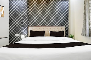 A bed with a headboard, a bedside lamp, and a wall with a geometric pattern.