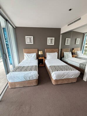 Ein Hotelzimmer mit zwei Betten, einem Fenster und einem Spiegel.