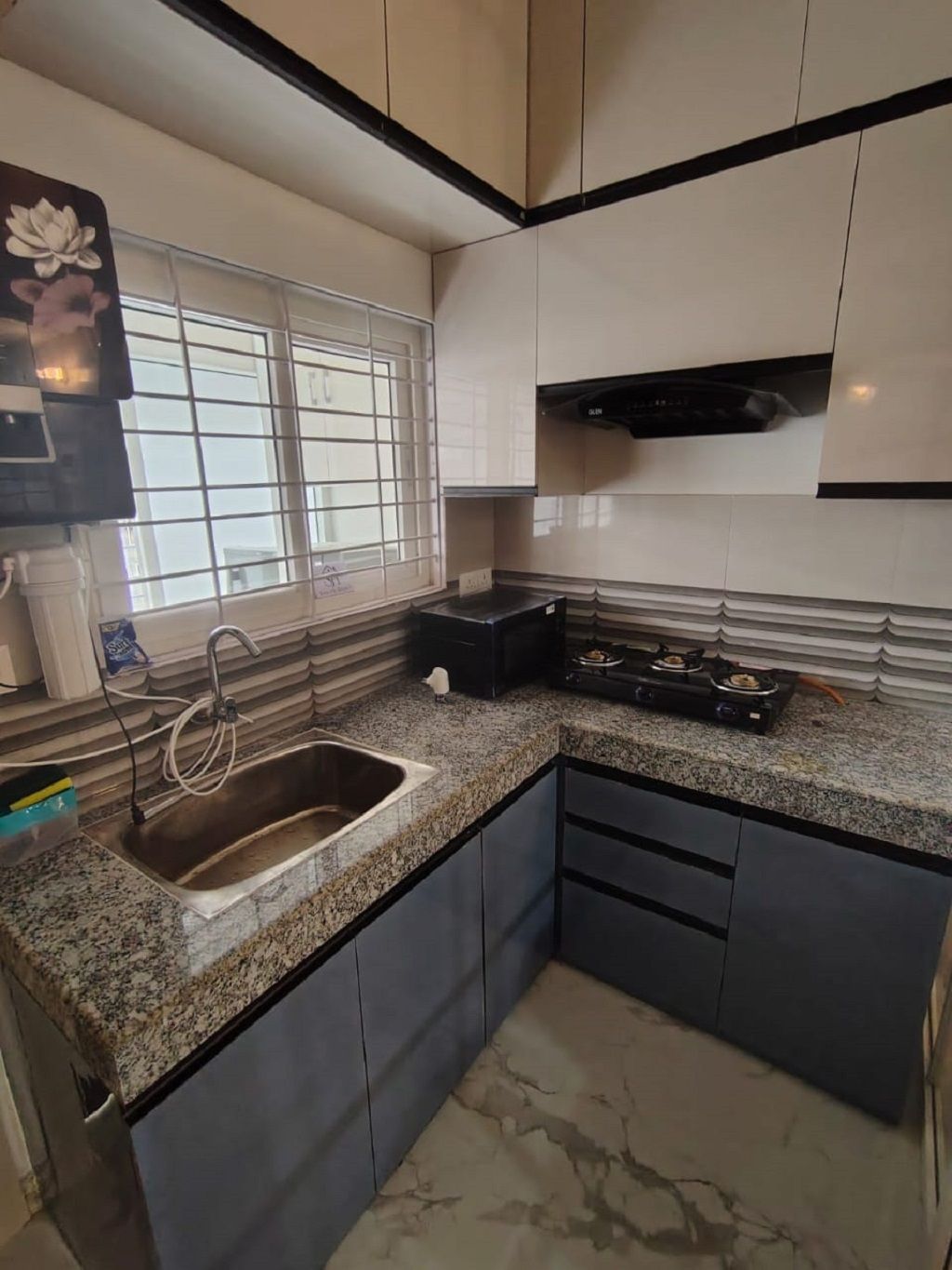 Cozinha com bancada de granito, pia de aço inoxidável e fogão a gás.