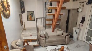 Ein modernes Wohnzimmer mit Marmorboden, einer Sofagarnitur, einem Couchtisch und einer Holztreppe.