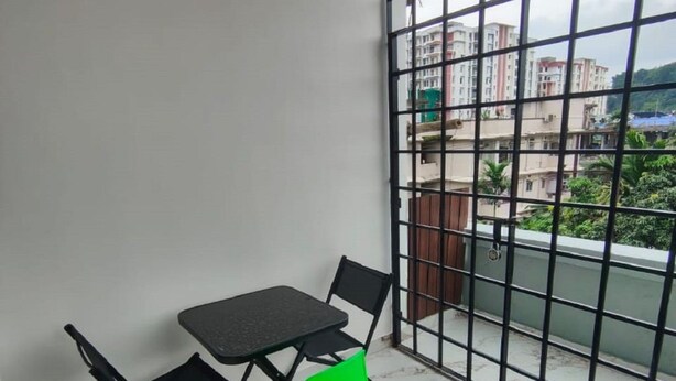 Ein Balkon mit Tisch und Stühlen und Blick auf Gebäude, ausgestattet mit einem Metallgeländer.
