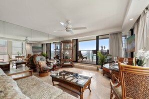 A spacious living area with a large window, a ceiling fan, and a balcony with a view of the ocean. - Oceanfront 1BD with Unobstructed Ocean, Lanai & Island Views & Pool -Kaleialoha 415 (Lahaina)