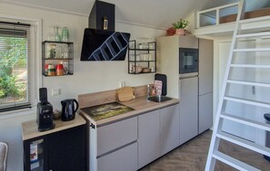 A compact kitchen with a built-in microwave, a coffee maker, and a small refrigerator. - 2 bedroom cozy home in Wenum-Wiesel (Wenum-Wiesel)