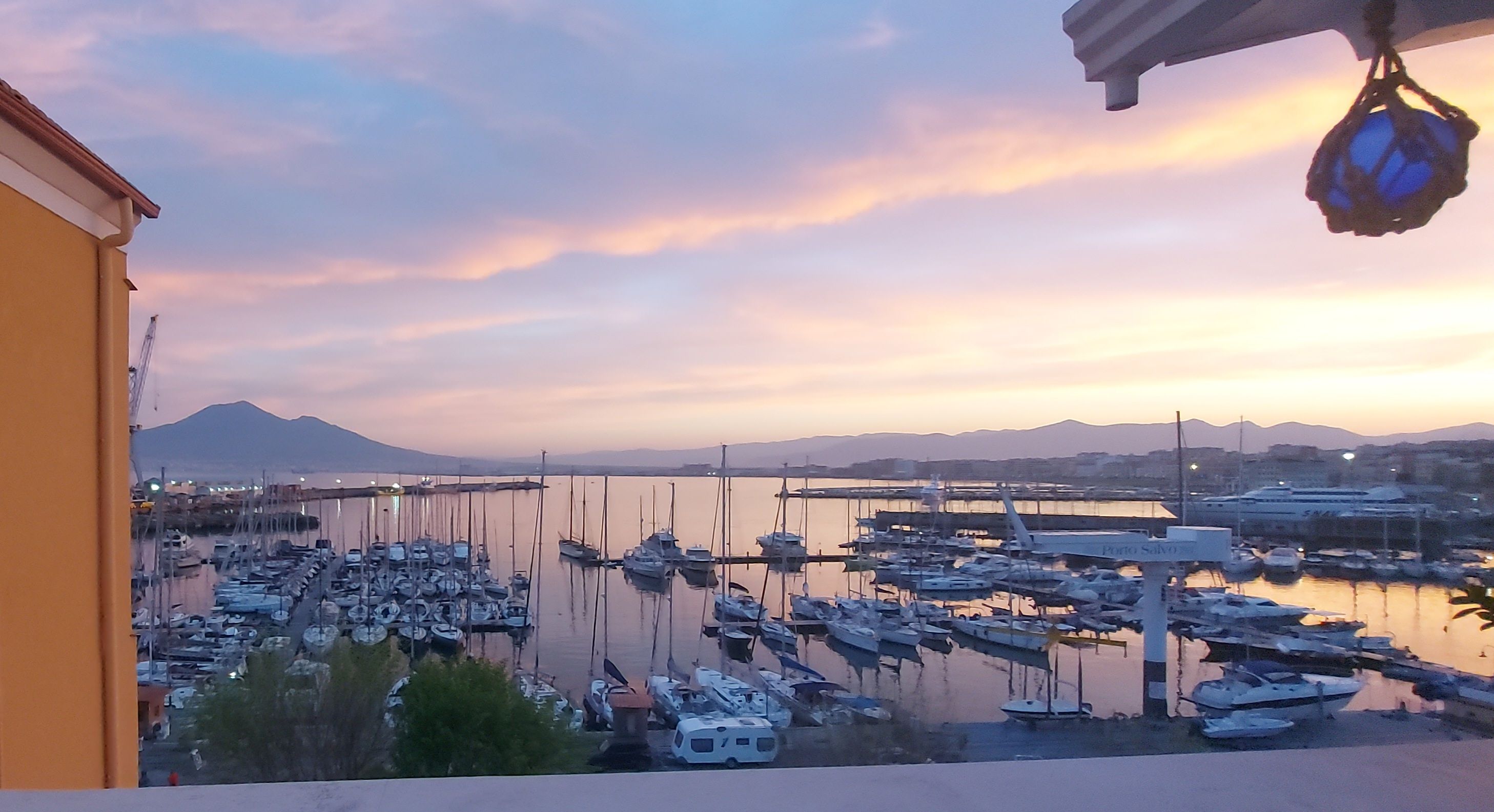 A marina with boats docked, a mountain in the background, and a clear sky.