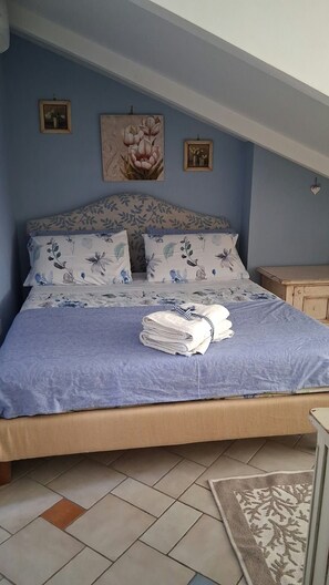 A bedroom with a bed, pillows, a folded towel, and a nightstand. - Coralinetiny (Castellammare di Stabia)