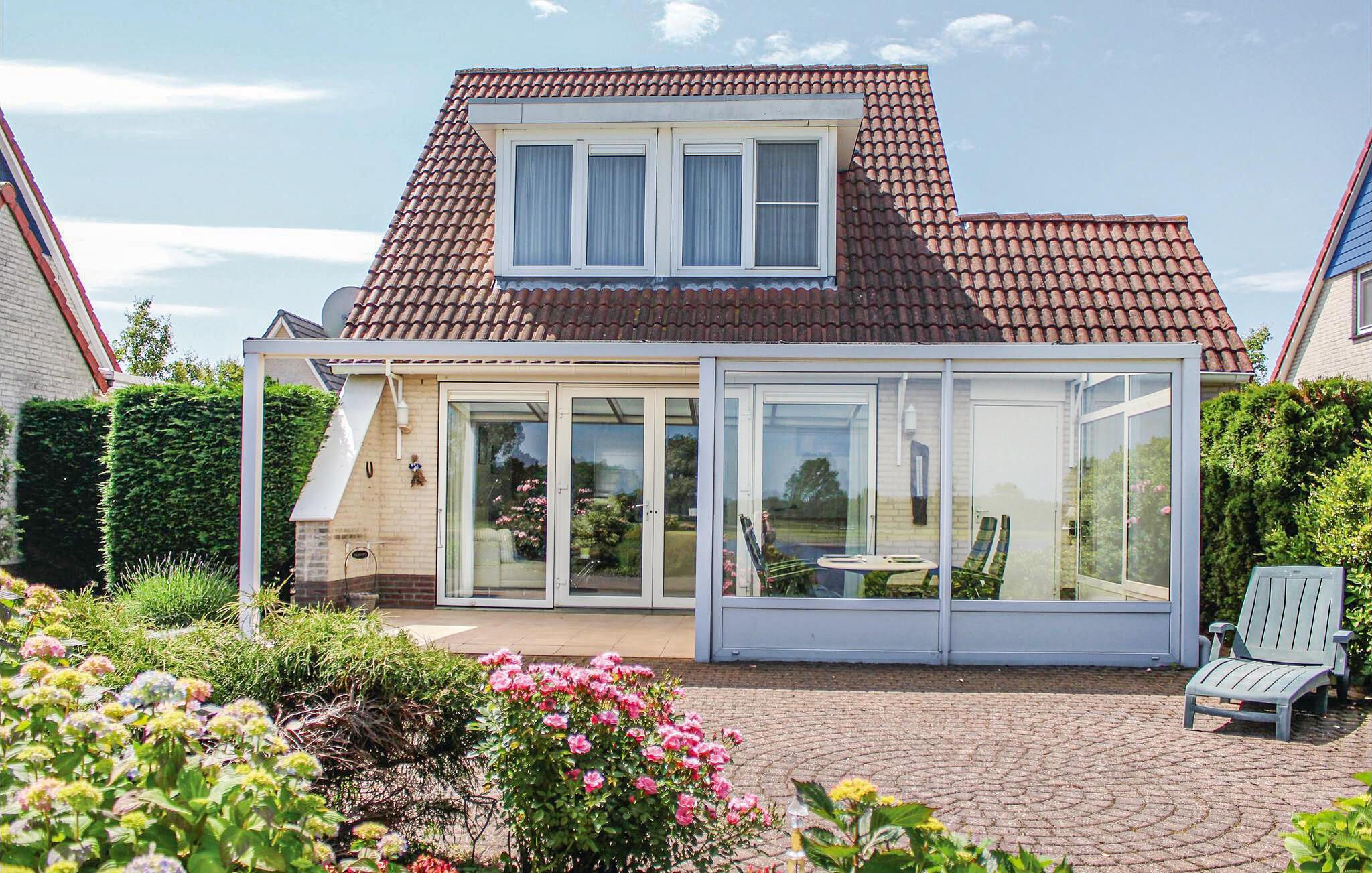 A house with a conservatory, a tiled roof, and a garden with flowers.