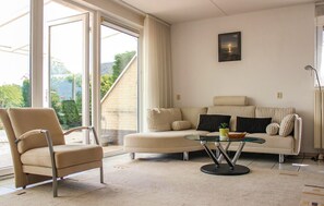 Ein Wohnzimmer mit einer Couch, einem Sessel und einem Glastisch.