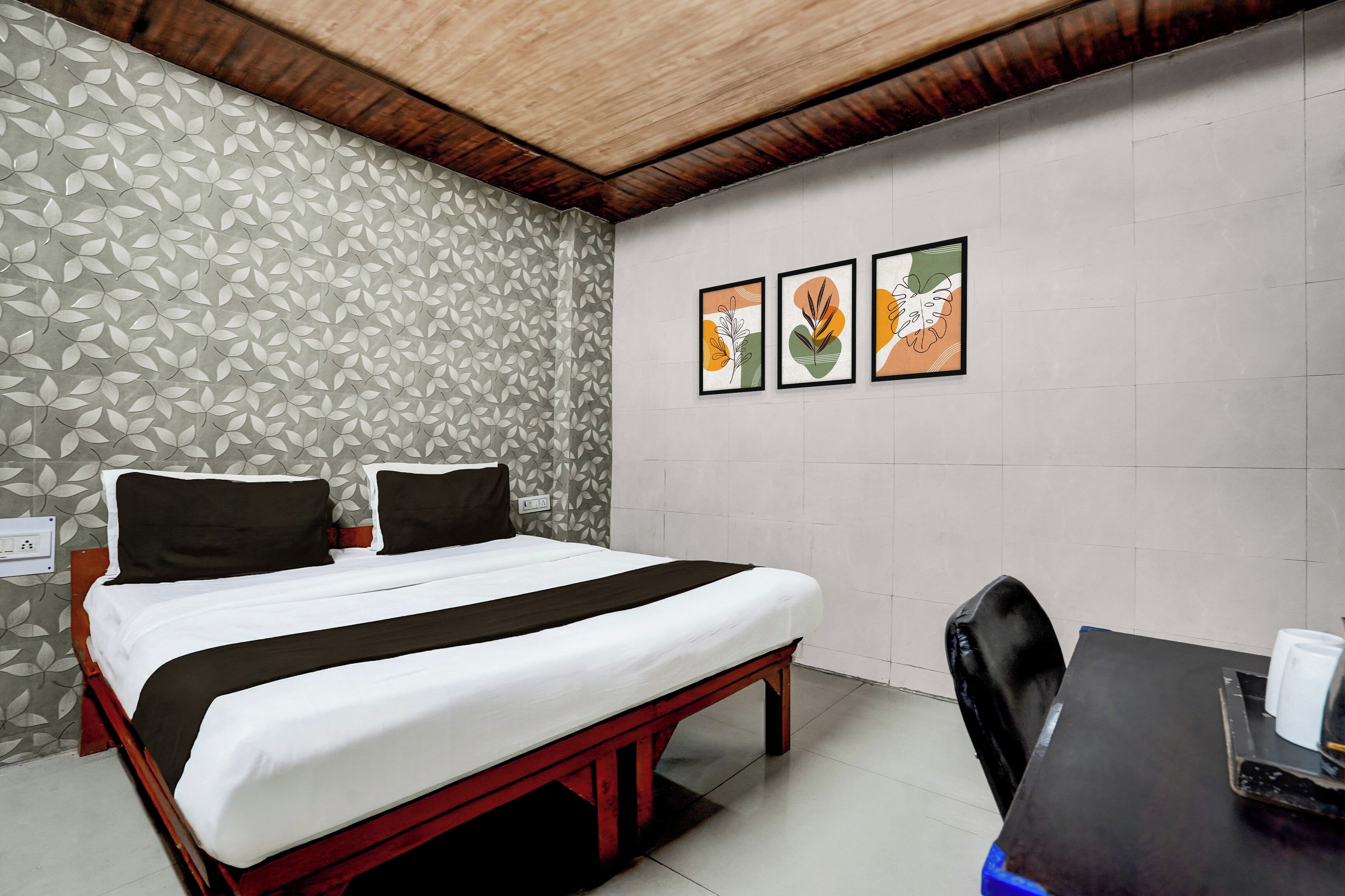 Una habitación de hotel con cama, escritorio y silla. Hay tres cuadros enmarcados en la pared.