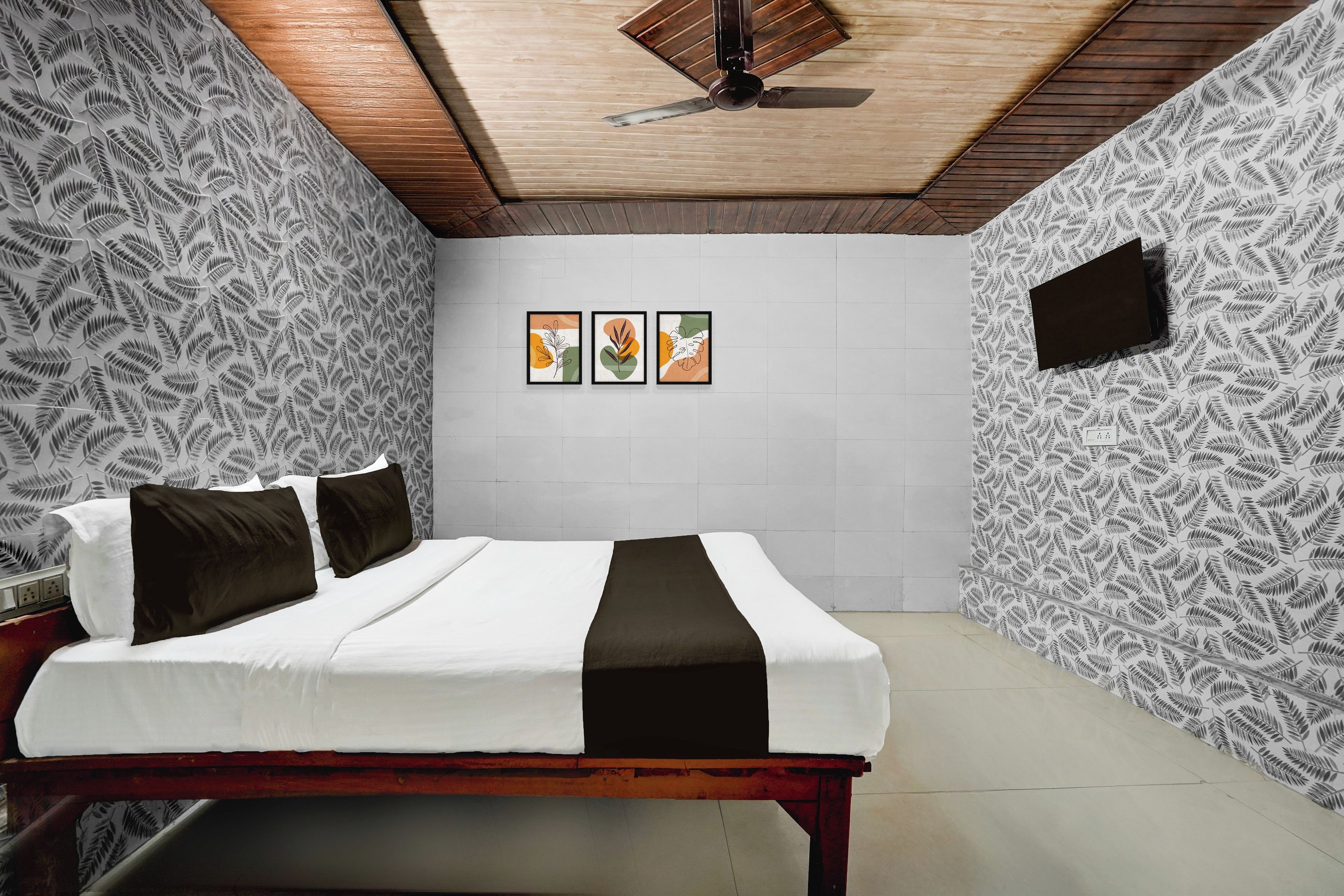 A bedroom with a bed, a ceiling fan, and three framed artworks on the wall.