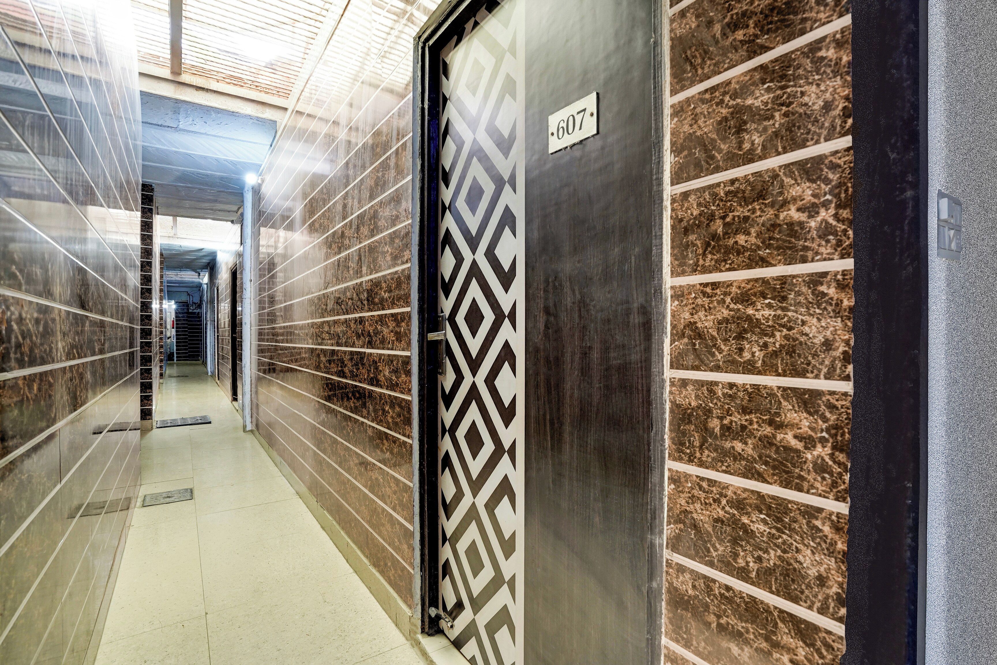 A corridor with a patterned door, a number sign, and a tiled floor.