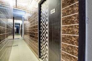 A corridor with a patterned door, a number sign, and a tiled floor. - Hotel O Hindon Airport Ghaziabad (Ghaziabad)