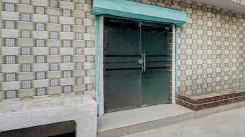 A building facade with a patterned brick wall and a large glass door with a teal awning.