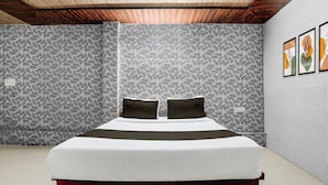 Una camera da letto con un letto, soffitto in legno, carta da parati decorata e opere d'arte alle pareti.