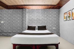 Quarto com cama, teto de madeira, papel de parede estampado e obra de arte na parede.