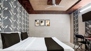 Una stanza con un letto, un ventilatore a soffitto e due opere d'arte appese al muro.