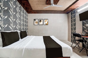 Quarto com cama, ventilador de teto e duas obras de arte emolduradas na parede.