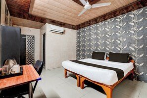 Quarto com cama, escrivaninha, cadeira, ventilador de teto e ar condicionado.
